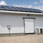 Technicien WOW2000 devant une chambre froide alimentée par des panneaux solaires